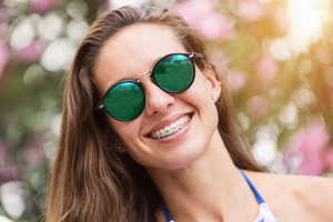 Woman in sunglasses showing off smile with braces